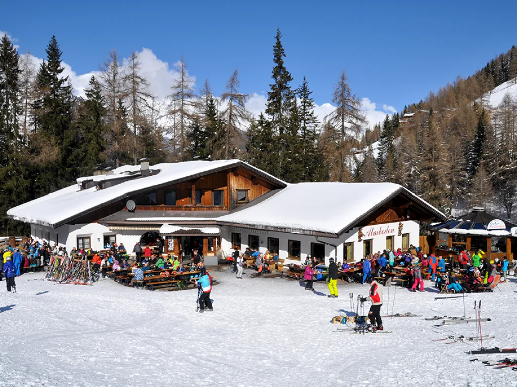 Skihütte mit vielen abgestellten Skiern davor.